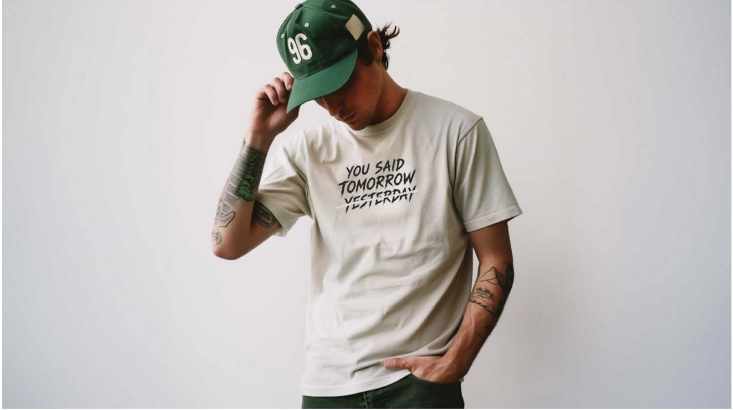 Person wearing a white t-shirt with text and a green cap on a plain background